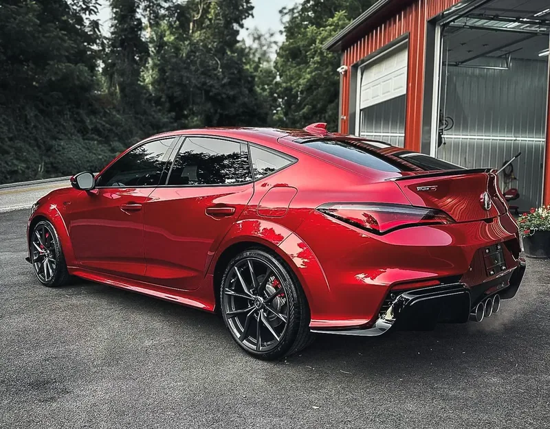 A red car is parked in front of a garage.