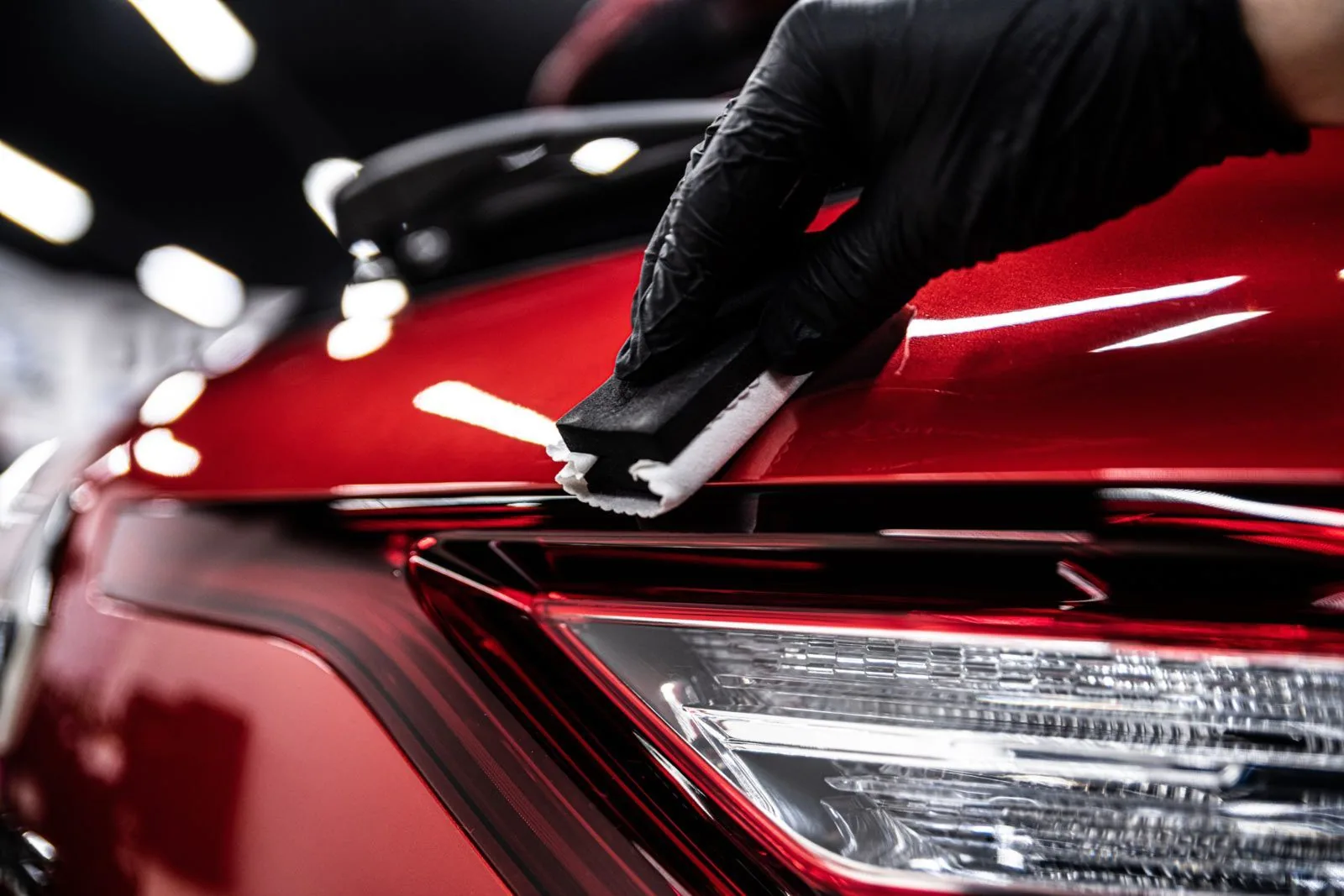 Ceramic coating being applied to a red car