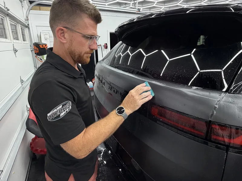 An Elite Finish installer applying matte paint protection film to a black SUV