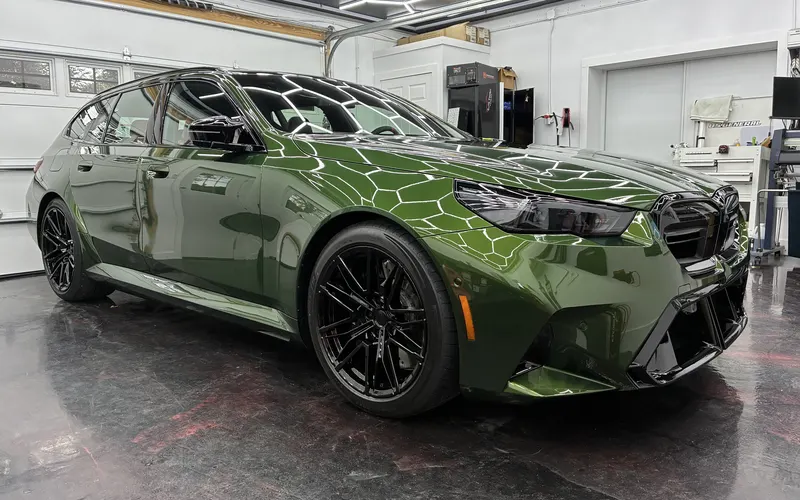 A green BMW M5 Touring with PPF and ceramic coating in the Elite Finish shop