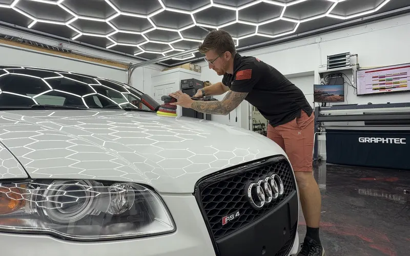 An Elite Finish technician polishing the hood of a white Audi RS4