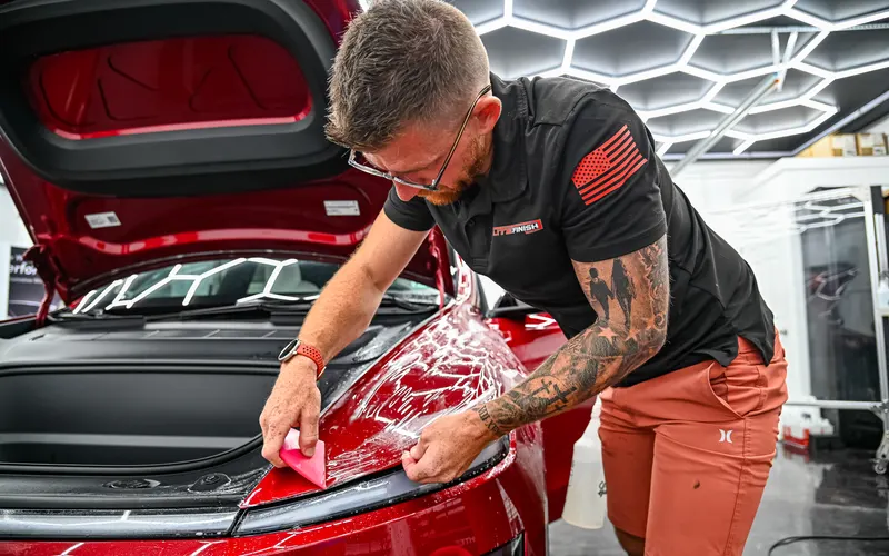 Paint protection film being installed on a red Tesla Model Y